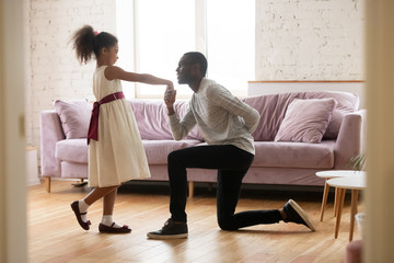 Father and daughter dancing while he’s on on knee holding her hand