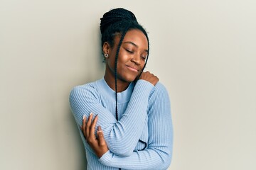 Woman standing against a wall hugging herself showing comfort to herself