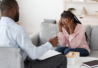 Image of guy providing therapy sessions to woman on sofa